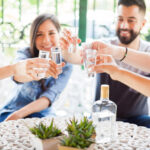 Five friends raising their glasses and making a toast with tequila shots during a party outdoors